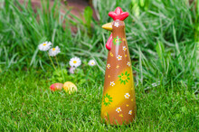 Chocolate Rooster In The Grass On A Background Of Daisies And Eggs