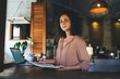 © BullRun - Portrait of Caucaisan female student with education textbook and netbook e learning at cafe terrace, skilled freelance copywriter using notepad and modern laptop computer working remotely
