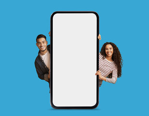 Poster - Check This. Happy Arab Couple Standing Behind Blank Smartphone With White Screen