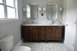 Clean bright bathroom with dark wood vanity and white marble sinks in a new home or after a remodel