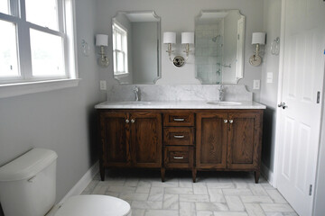 Clean bright bathroom with dark wood vanity and white marble sinks in a new home or after a remodel