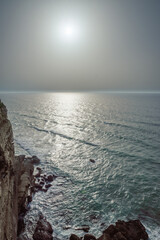 Wall Mural - rocky coastline, ocean and sunlight shines through gaps in clouds. beautiful nature background.