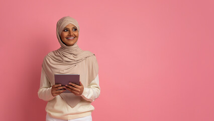 Wall Mural - Smiling Muslim Woman In Hijab Holding Digital Tablet And Looking Aside