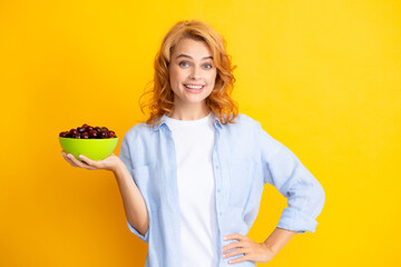 Wall Mural - Portrait of woman with cherries on yellow studio isolated background.