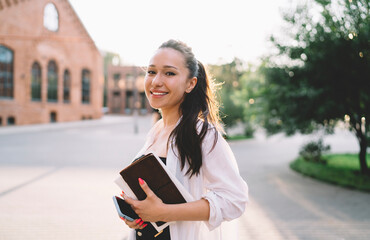 Smiling woman with notebook on street