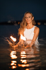 Wall Mural - Caucasian woman dancing with fire in the water. Fire show at sea. Acrobatics on the beach. Yoga and relaxation at sunset. Spectacular circus performance. model body. High quality FullHD footage. 