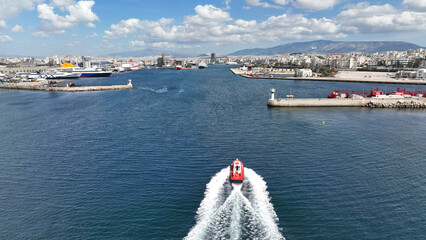 Wall Mural - Aerial drone photo of red pilot boat cruising in high speed in Mediterranean deep blue sea reaching famous port of Piraeus, Attica, Greece
