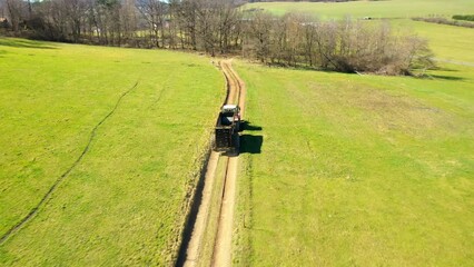 Wall Mural - A tractor with a semi-trailer driving on a dirt road. Agricultural machinery is a source of greenhouse gas emissions.