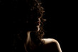 Sensual portrait silhouette of beautiful curly woman in backlight on a black background