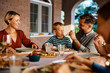 © Drazen - Happy father feeds his son during family lunch on patio.