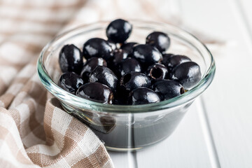 Poster - Pitted black olives in bowl on kitchen table.