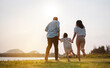 © Kiattisak - Happy family in the park sunset light. family on weekend running together in the meadow with river Parents hold the child hands.health life insurance plan concept.