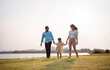 © Kiattisak - Happy family in the park sunset light. family on weekend running together in the meadow with river Parents hold the child hands.health life insurance plan concept.