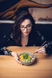 © pridneprovskiy - Cheerful young asian girl eating healthy food on dark background