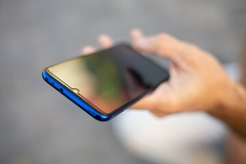 Closeup image of male hands with smartphone, searching internet or social networks, blurred background