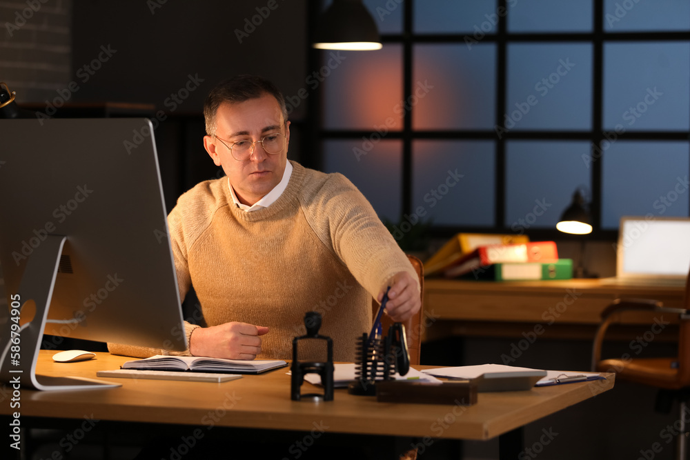 Mature accountant working in office at night