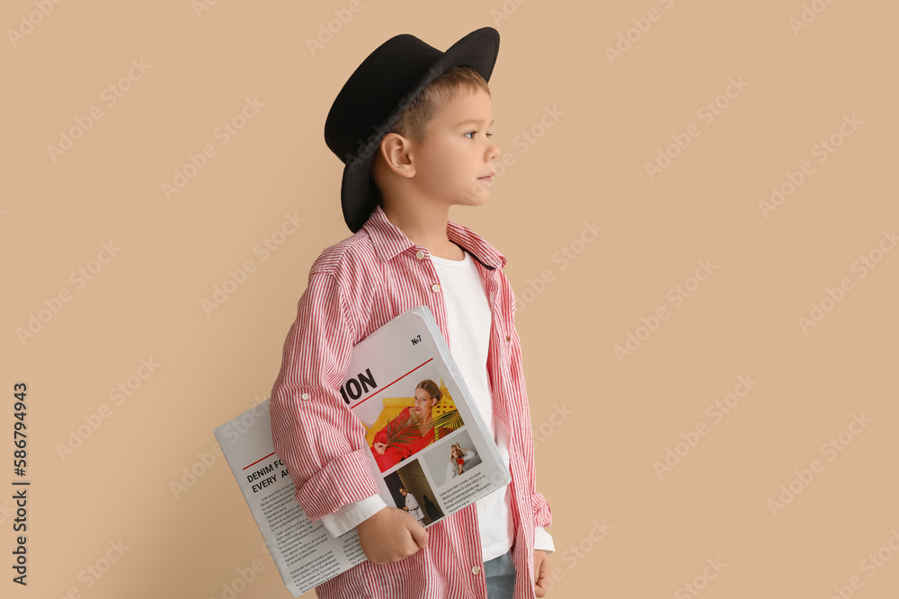 Cute little stylist with newspaper on beige background