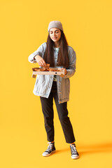 Poster - Young woman with box of tasty pizza on yellow background