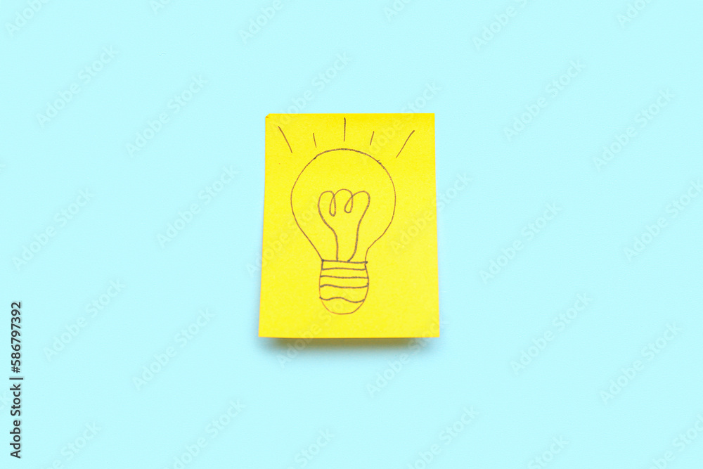 Sticky paper with drawn light bulb on blue background. Insight concept