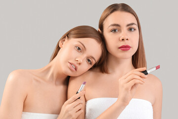 Poster - Young women with lipsticks on grey background, closeup