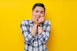 © Bangun Stock Photo - Young scared Asian man in plaid shirt looking camera biting his nails and fingers isolated on yellow background. people lifestyle concept