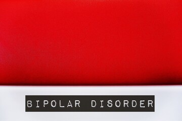 Red wall background with text BIPOLAR DISORDER on blur foreground, concept of serious shifts in mood, energy, thinking and behavior from extreme highs of mania to lows of depression