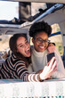 © Raul Mellado - two young women taking a selfie photo lying in a camper van, concept of weekend getaway with best friend and road trip adventure