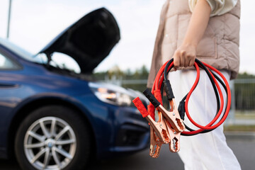 close-up of a car voltmeter in the hands of a woman against the background of a broken car