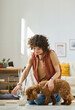 © AnnaStills - Vertical image of young woman feeding her little dog pouring food in bowl in the room