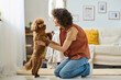 © AnnaStills - Young happy woman playing with her little dog in the room at home