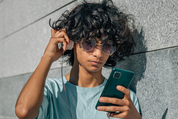 Wall Mural - young man with headphones and mobile phone on the wall