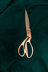 Steel tailor scissors on green natural fabric. Content for sewing workshops, ateliers for tailoring clothes