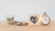 For elderly old people health care concept. White heart with hospital or clinic and disability person, elderly sign on wooden cube block and vintage clock blurred coins