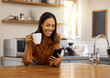 © Nina/peopleimages.com - Smile, kitchen and woman with phone, coffee and relax while browsing internet, checking social media or reading email. Chat, connect and work from home lifestyle, female on tea break in apartment.