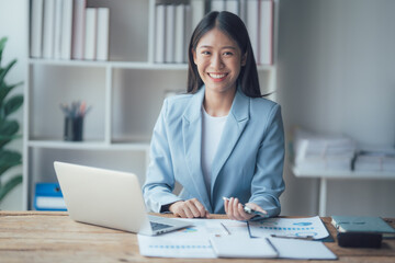 Asian businesswoman talking on phone, using laptop, looking at screen, entrepreneur manager consulting client by call, looking at computer screen, discussing