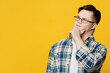 Young minded thoughtful man with down syndrome wearing glasses casual clothes looking aside on area props up chin isolated on pastel plain yellow color background. Genetic disease world day concept.
