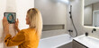 © Angelov - Woman using smartphone monitor to control home connectivity interface