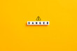 © Cagkan - White letter blocks on yellow background with the word danger and a warning sign. Risk and danger concept.