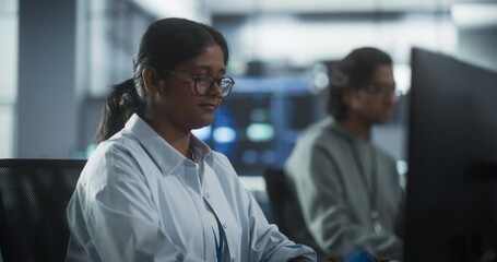 Young Indian Colleagues Working on Computers and Talking at a Workplace. Smart Female and Male Software Developers Focused on Coding and Analyzing a New Technical Feature