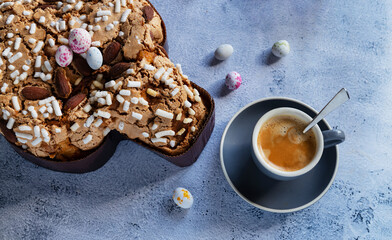 Colomba pastries, a cup of espresso coffee and chocolate colored quail eggs on a stone table. Italian traditional food with hard shadows