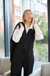 © Maria Vitkovska - Portrait of attractive stylish business woman wearing black suit talking on mobile phone in modern office. Technology, successful business concept