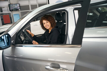 Wall Mural - Happy multiracial shopper sits in salon of brand new car