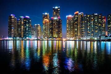 Wall Mural - Busan Marina city skyscrapers illuminated in night with reflection in water, South Korea