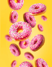 Levitating Donuts With Sprinkles On A Yellow Background. Modern Food Concept. Advertisement For A Pastry Shop Or Cafe.
