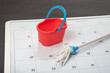 Small bucket and mop on the calendar. Concept of general cleaning. Planned cleanup.