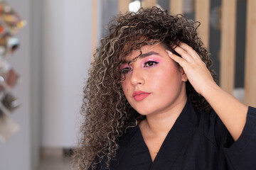 Facial makeup and professional curly hair treatment completed. Woman shows her beauty treatment.