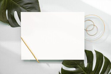Wall Mural - Styled summer wedding desktop stationery mockup. Blank greeting and invitation card. Green tropical leaves with empty space.