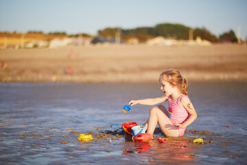 Sticker - Preschooler girl playing on the sand beach at Atlantic coast of Normandy, France