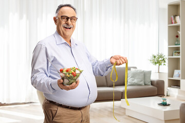 Poster - Mature man holding a salad and a measuring tape in a living room