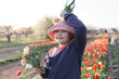 Young preteen girl picking up tulips on the country field, she is happy and smiling, sunset light outdoor scene.